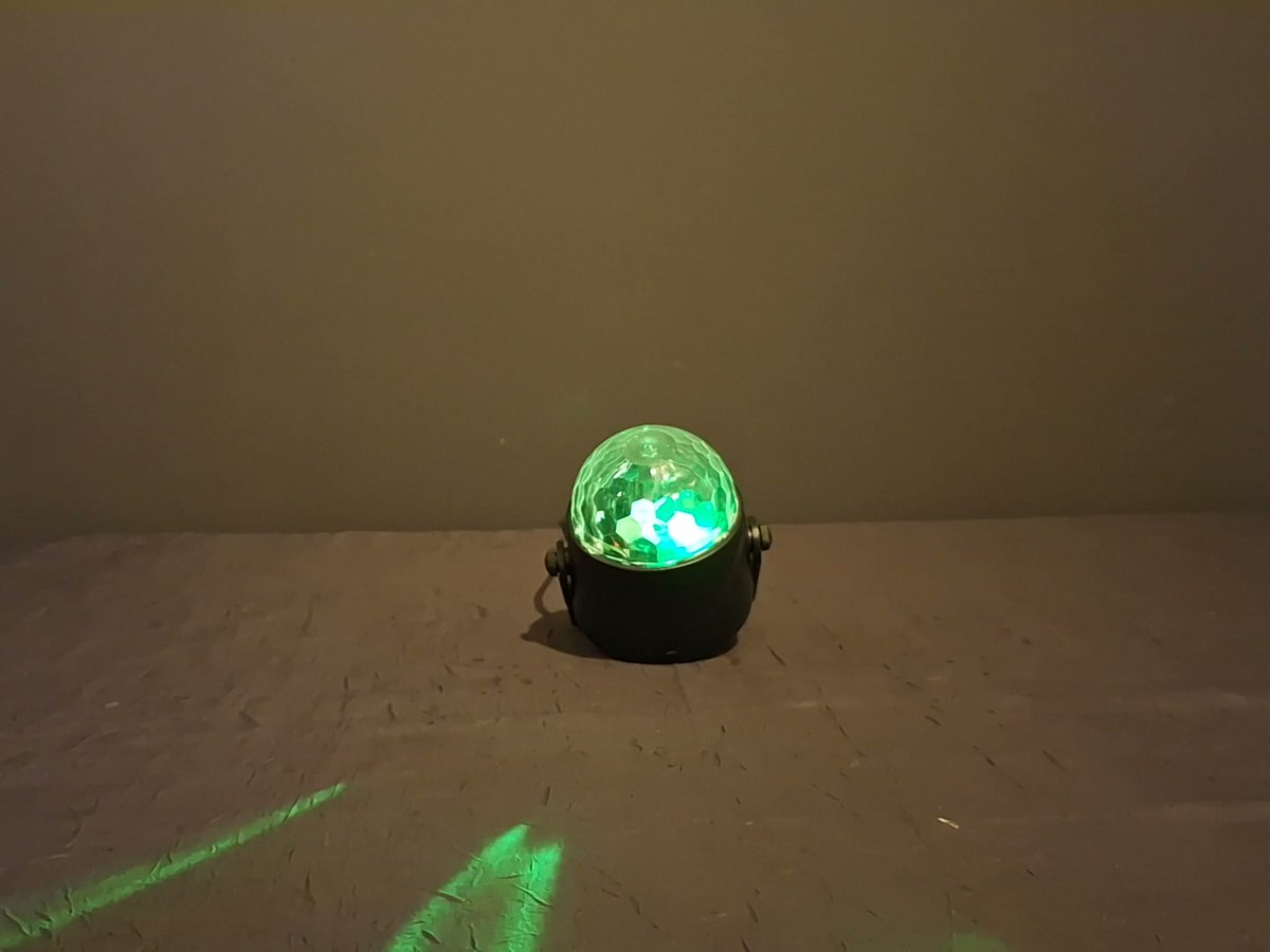 Petite boule disco LED à facettes, allumée, posée sur son socle