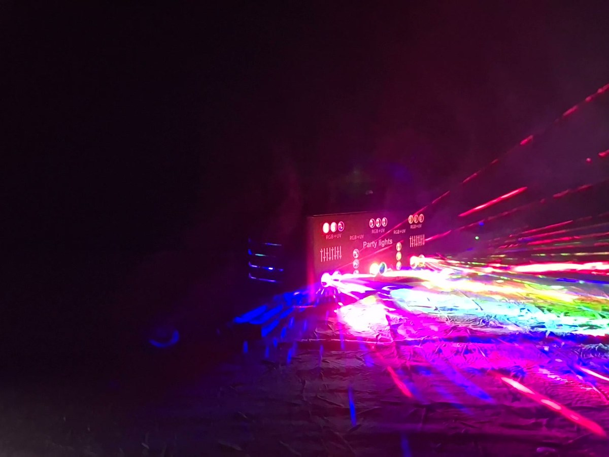 Faisceaux laser verts et magenta traversant une pièce sombre